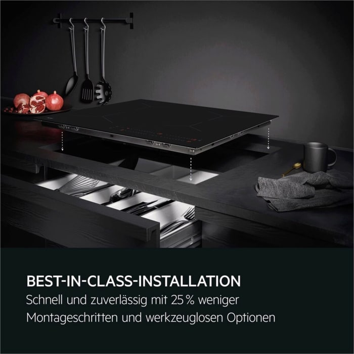 Ein Kochfeld wird über einer Küchenarbeitsplatte installiert, darunter offene Schubladen mit Küchenutensilien.